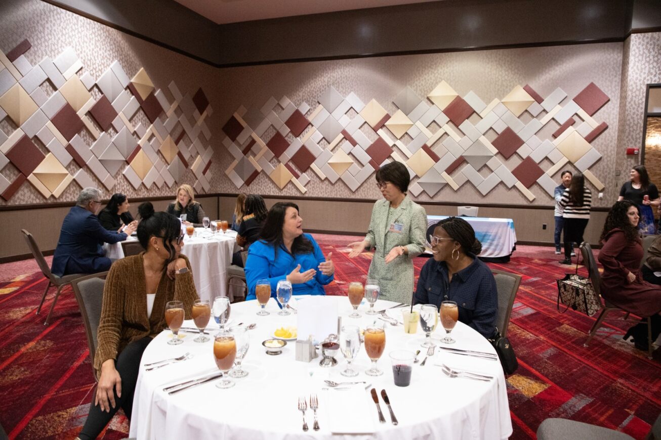 Four women sit around a table talking at the appreciation dinner